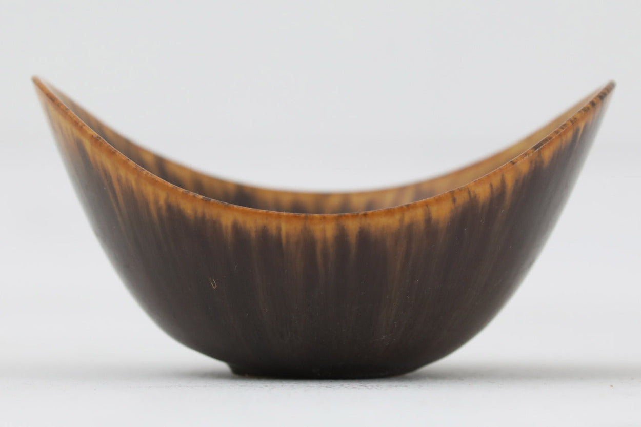 フィンランド人で彫刻家の父と、デンマーク人で陶芸家の母の元に育つGunnarNylundはデンマークで建築を学んだ後、Bing&amp;amp;Grondahl窯、スウェーデンRorstrand窯に就業し、多くの作品を生み出しています。彼の作品は独特な流線型と釉薬が特徴で世界中で重宝されています。AROボウルは彼の最も代表的な作品で、その緩やかな美しいカーブが特徴です。また、さまざまな表情をみせる釉薬がコレクターにも人気がある理由です。