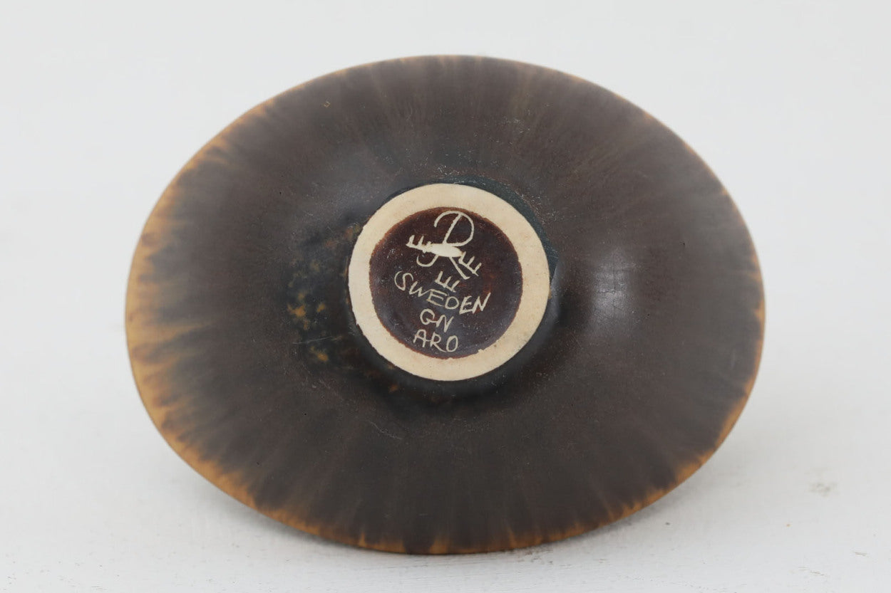 フィンランド人で彫刻家の父と、デンマーク人で陶芸家の母の元に育つGunnarNylundはデンマークで建築を学んだ後、Bing&amp;amp;Grondahl窯、スウェーデンRorstrand窯に就業し、多くの作品を生み出しています。彼の作品は独特な流線型と釉薬が特徴で世界中で重宝されています。AROボウルは彼の最も代表的な作品で、その緩やかな美しいカーブが特徴です。また、さまざまな表情をみせる釉薬がコレクターにも人気がある理由です。