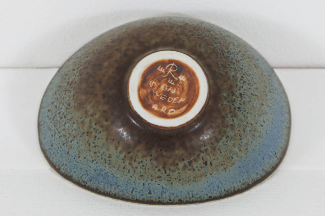 フィンランド人で彫刻家の父と、デンマーク人で陶芸家の母の元に育つGunnarNylundはデンマークで建築を学んだ後、Bing&amp;amp;Grondahl窯、スウェーデンRorstrand窯に就業し、多くの作品を生み出しています。彼の作品は独特な流線型と釉薬が特徴で世界中で重宝されています。AROボウルは彼の最も代表的な作品で、その緩やかな美しいカーブが特徴です。また、さまざまな表情をみせる釉薬がコレクターにも人気がある理由です。