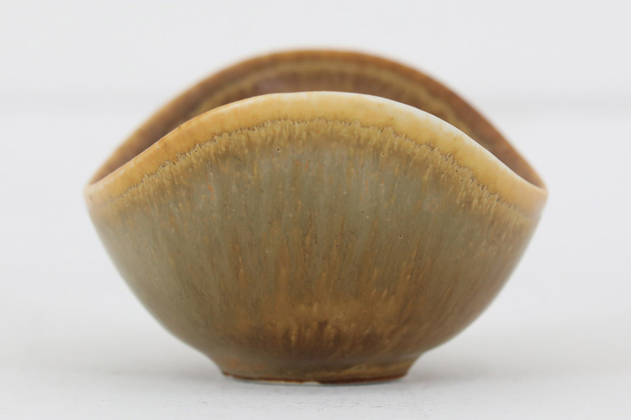 フィンランド人で彫刻家の父と、デンマーク人で陶芸家の母の元に育つGunnarNylundはデンマークで建築を学んだ後、Bing&amp;Grondahl窯、スウェーデンRorstrand窯に就業し、多くの作品を生み出しています。彼の作品は独特な流線型と釉薬が特徴で世界中で重宝されています。AROボウルは彼の最も代表的な作品で、その緩やかな美しいカーブが特徴です。また、さまざまな表情をみせる釉薬がコレクターにも人気がある理由です。