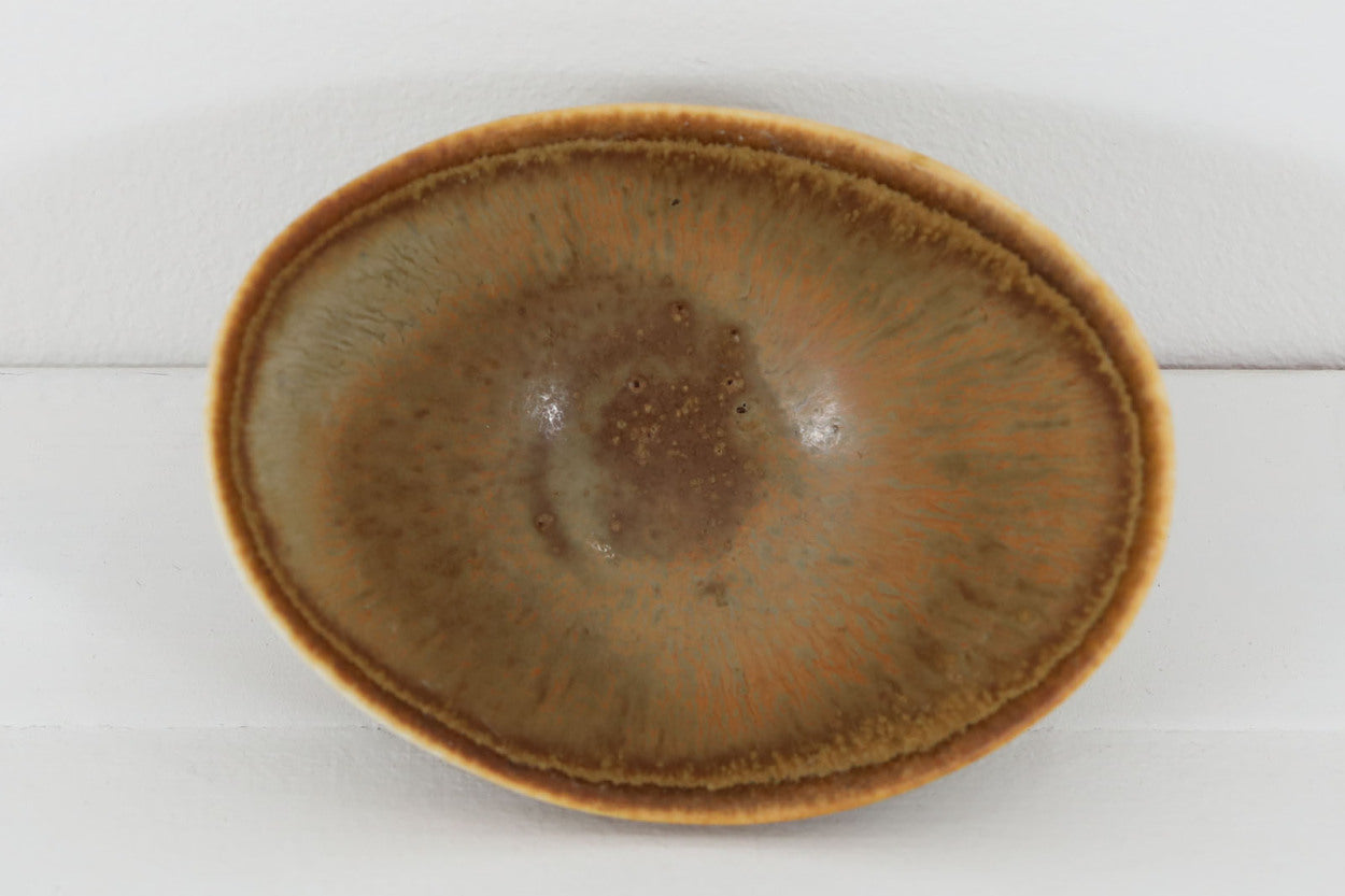 フィンランド人で彫刻家の父と、デンマーク人で陶芸家の母の元に育つGunnarNylundはデンマークで建築を学んだ後、Bing&amp;amp;Grondahl窯、スウェーデンRorstrand窯に就業し、多くの作品を生み出しています。彼の作品は独特な流線型と釉薬が特徴で世界中で重宝されています。AROボウルは彼の最も代表的な作品で、その緩やかな美しいカーブが特徴です。また、さまざまな表情をみせる釉薬がコレクターにも人気がある理由です。