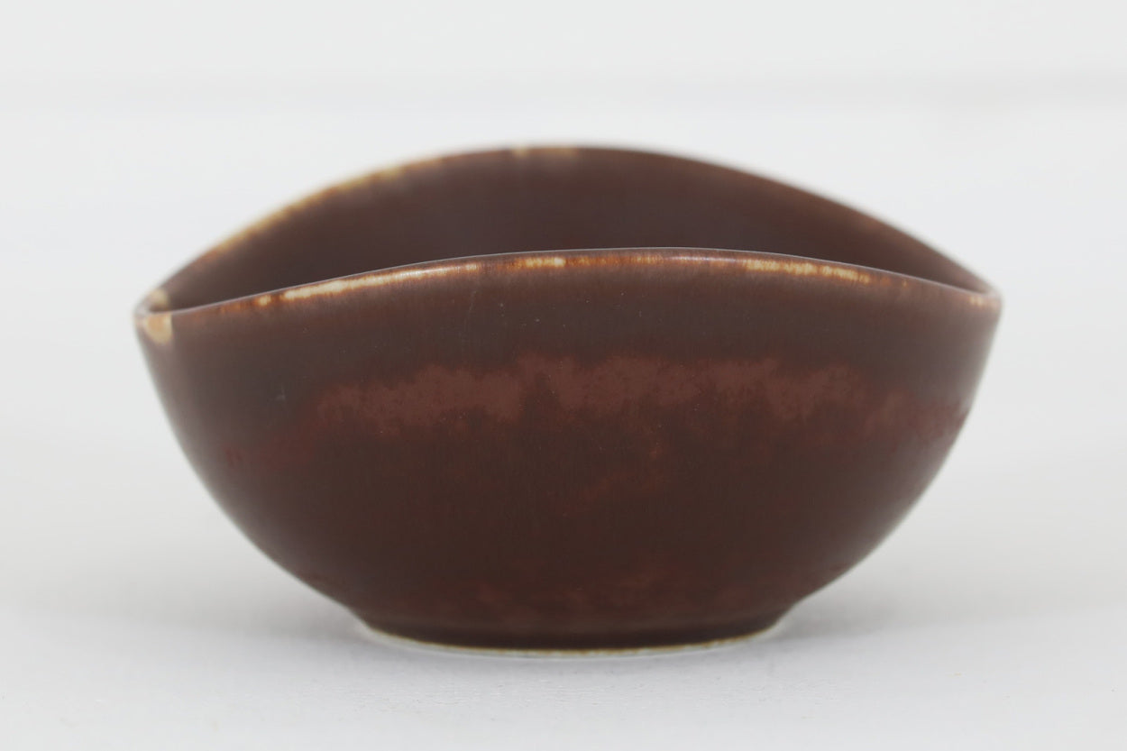 フィンランド人で彫刻家の父と、デンマーク人で陶芸家の母の元に育つGunnarNylundはデンマークで建築を学んだ後、Bing&amp;Grondahl窯、スウェーデンRorstrand窯に就業し、多くの作品を生み出しています。彼の作品は独特な流線型と釉薬が特徴で世界中で重宝されています。AROボウルは彼の最も代表的な作品で、その緩やかな美しいカーブが特徴です。また、さまざまな表情をみせる釉薬がコレクターにも人気がある理由です。