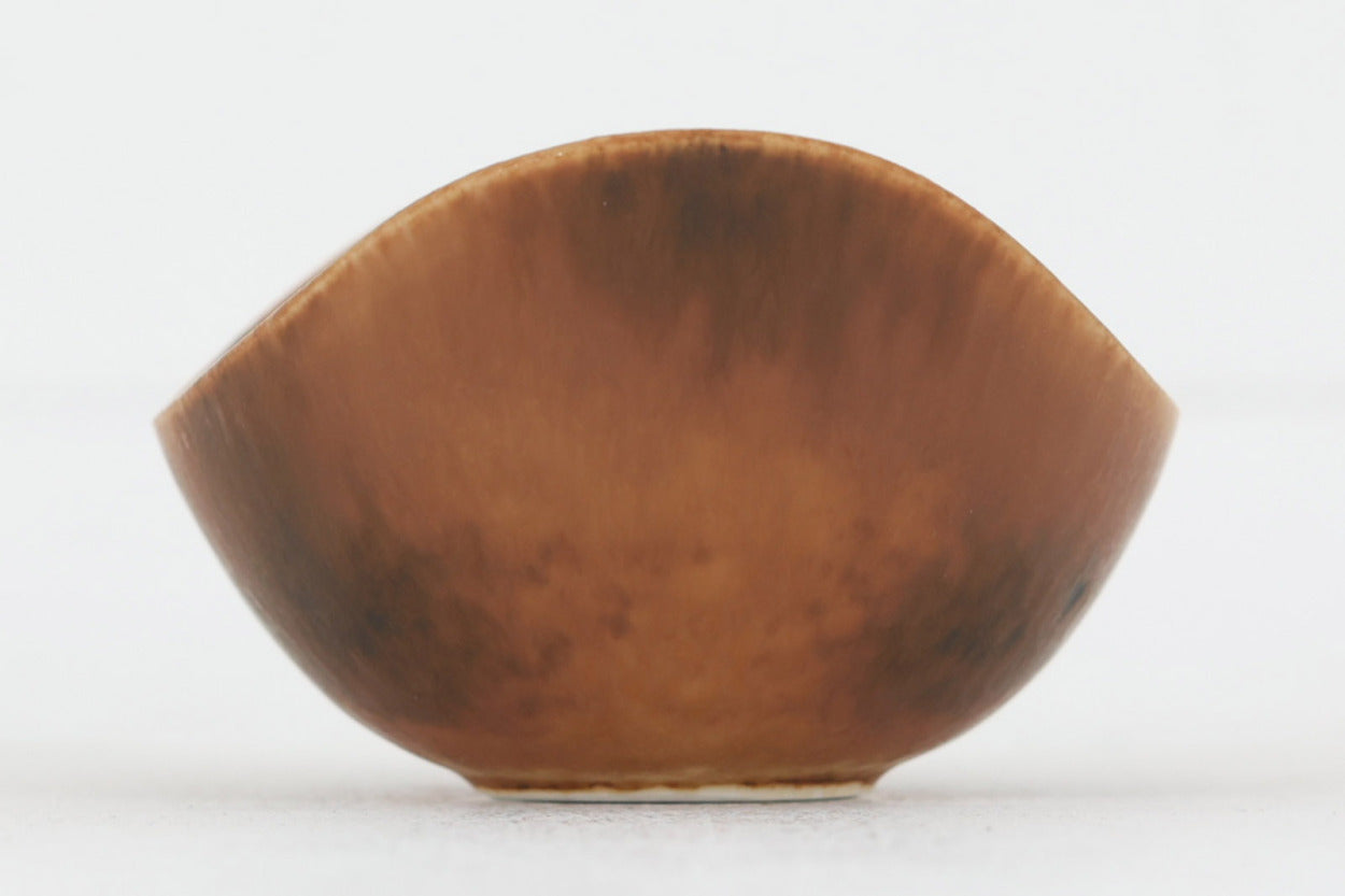 フィンランド人で彫刻家の父と、デンマーク人で陶芸家の母の元に育つGunnarNylundはデンマークで建築を学んだ後、Bing&amp;amp;Grondahl窯、スウェーデンRorstrand窯に就業し、多くの作品を生み出しています。彼の作品は独特な流線型と釉薬が特徴で世界中で重宝されています。AROボウルは彼の最も代表的な作品で、その緩やかな美しいカーブが特徴です。また、さまざまな表情をみせる釉薬がコレクターにも人気がある理由です。