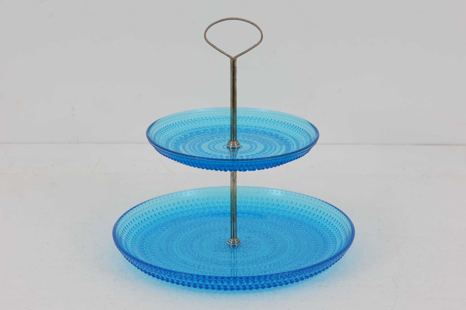 フィンランドのデザイナーOivaToikkaの代表作のカステヘルミのケーキスタンドです。露のしずくを表すこのシリーズは、しずくのような大小の凹凸を施し、光加減によってキラキラと輝くのが特徴です。現在復刻されているイッタラ製に見受けられるバリや歪みなどはなくヌータヤルヴィ製の品質の良さを感じさせます。