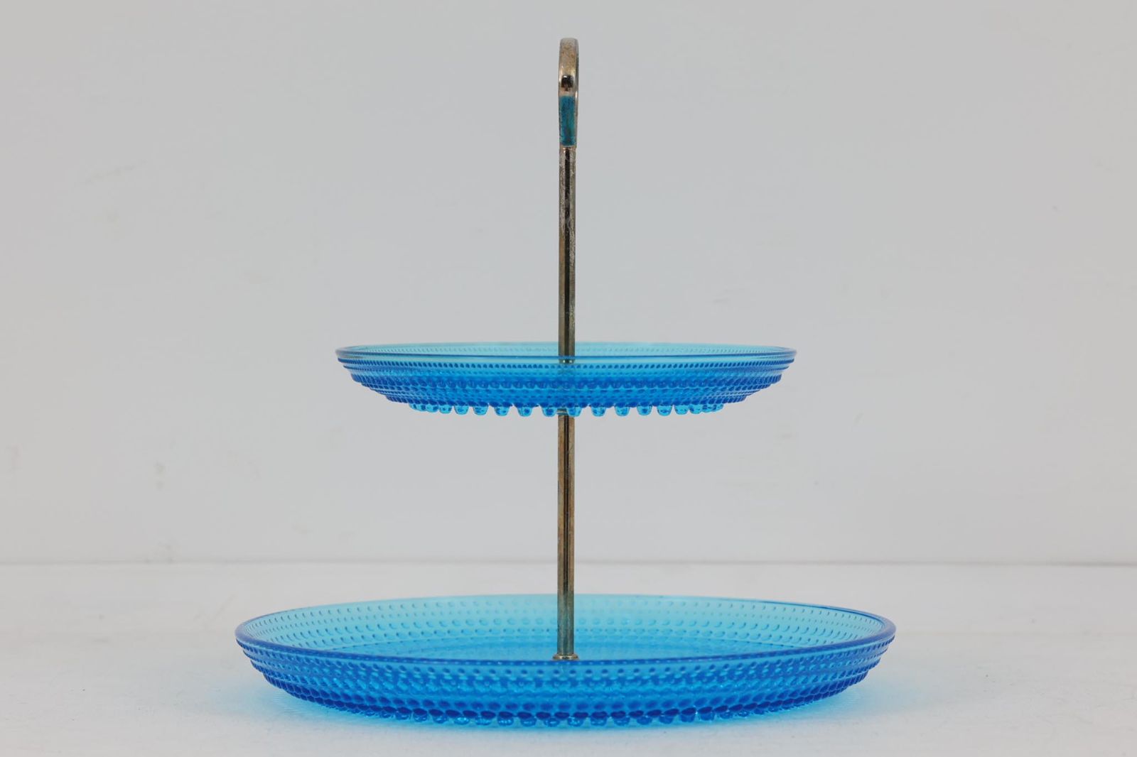 フィンランドのデザイナーOivaToikkaの代表作のカステヘルミのケーキスタンドです。露のしずくを表すこのシリーズは、しずくのような大小の凹凸を施し、光加減によってキラキラと輝くのが特徴です。現在復刻されているイッタラ製に見受けられるバリや歪みなどはなくヌータヤルヴィ製の品質の良さを感じさせます。